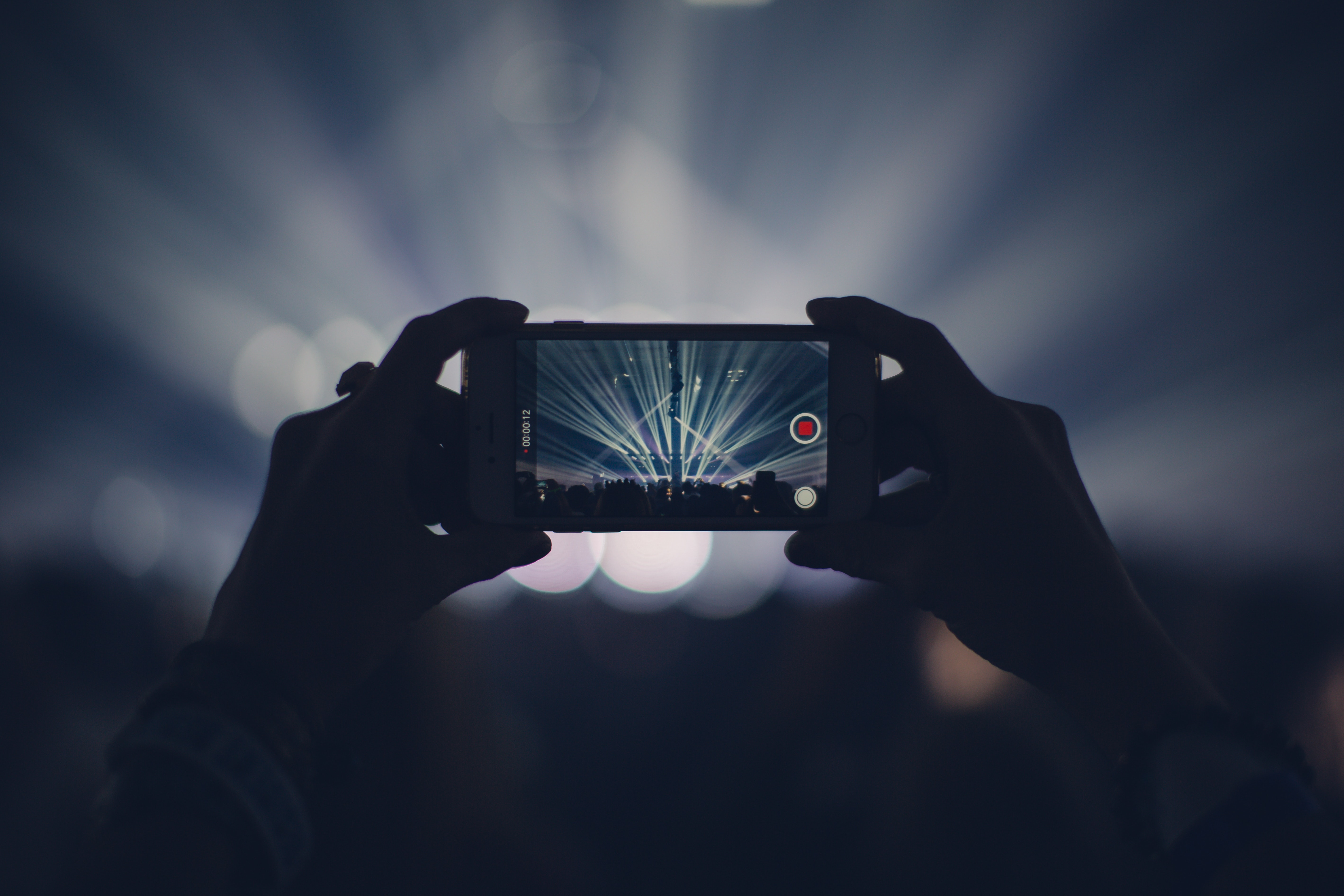 photo of a fan looking onto the stage with spotlights shining from the stage